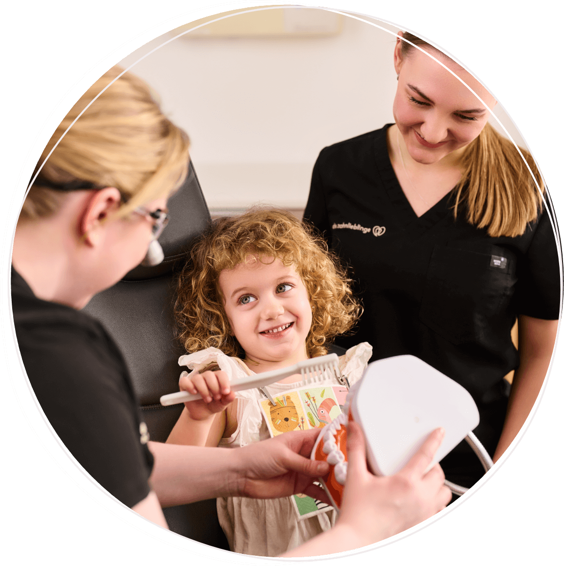 Zahnärztin Dr. Reuschl erklärt einem jungen Mädchen mithilfe eines großen Gebiss-Modells die richtige Vorgehensweise beim Zähneputzen