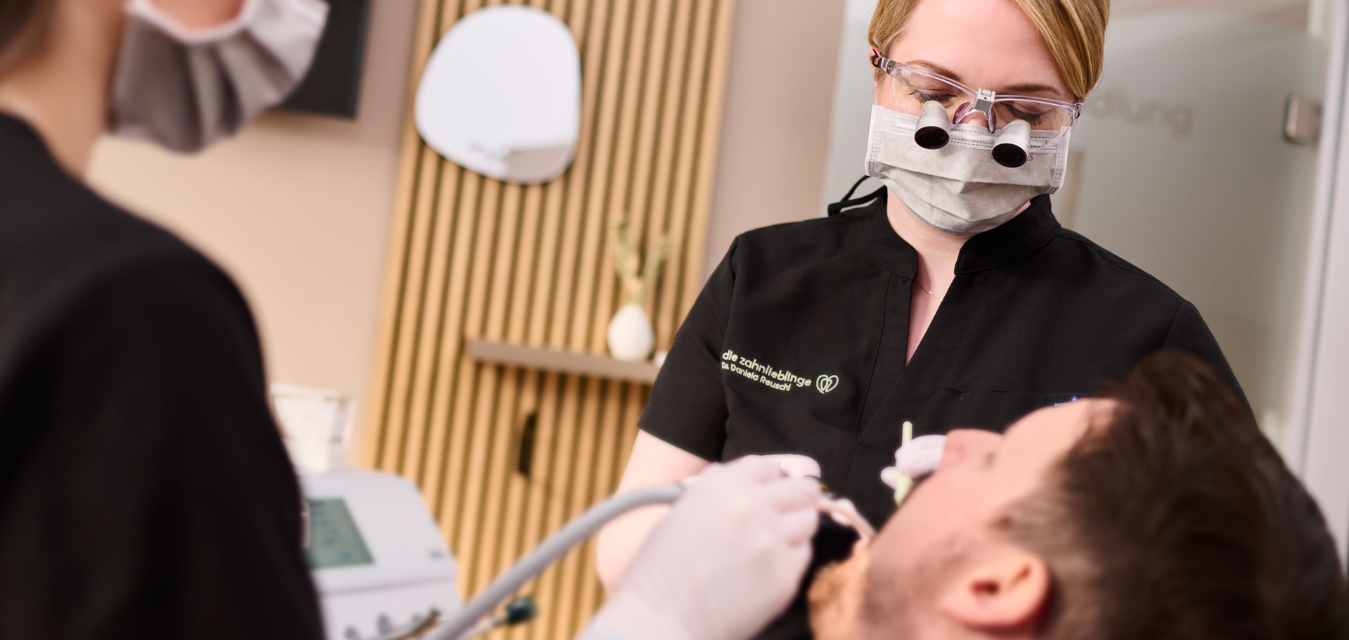 Zahnärztin Dr. Daniela Reuschl und ihre Assistentin behandeln einen Patienten